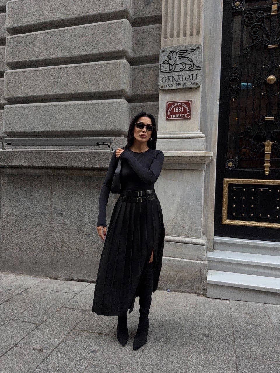 Onyx apparel: crimped lower-body attire, high rise, two-clasp belt, mid-calf drape, and a visible thigh split, worn b...