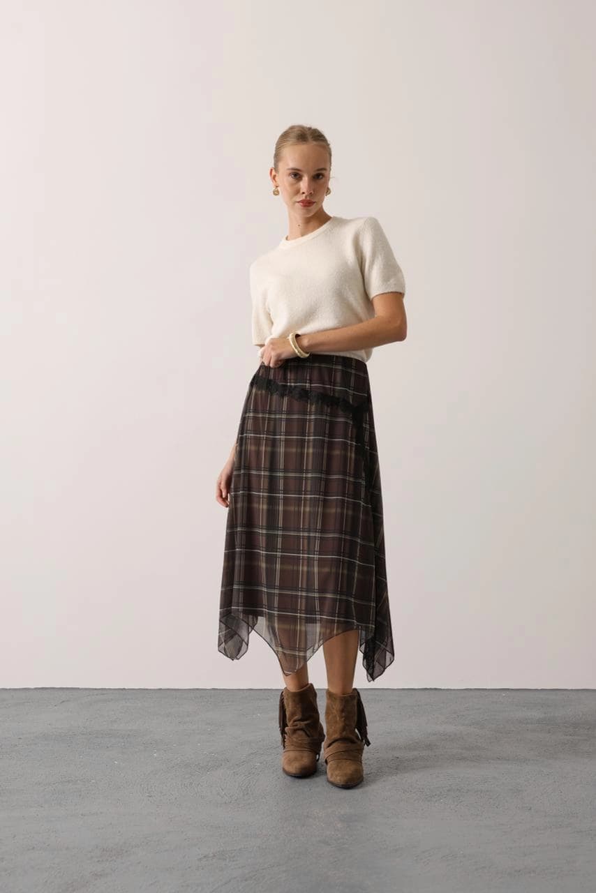 Flowy brown plaid midi skirt featuring a semi-sheer chiffon fabric, asymmetric handkerchief hem, and black lace trim ...