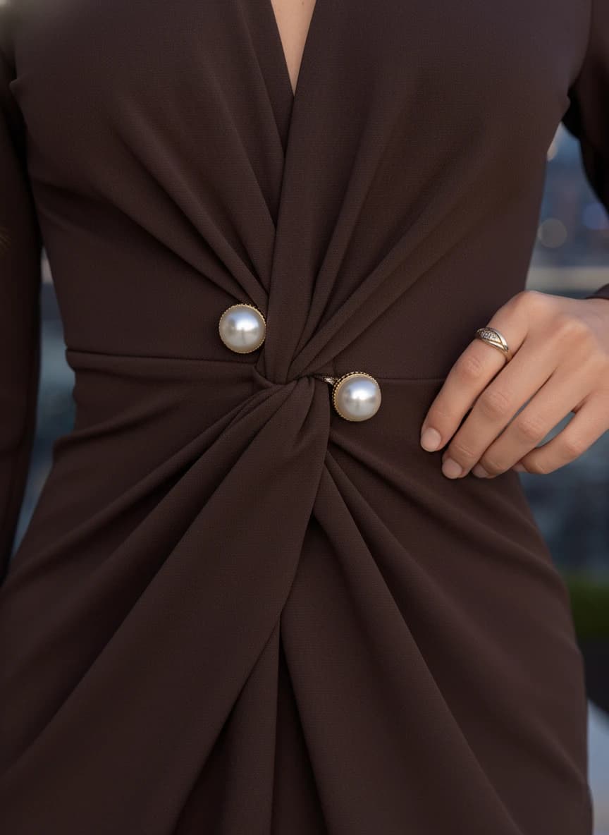 Sable hued attire, presenting a front knot detail secured by two spherical pearl buttons, with elegant fabric pleats.
