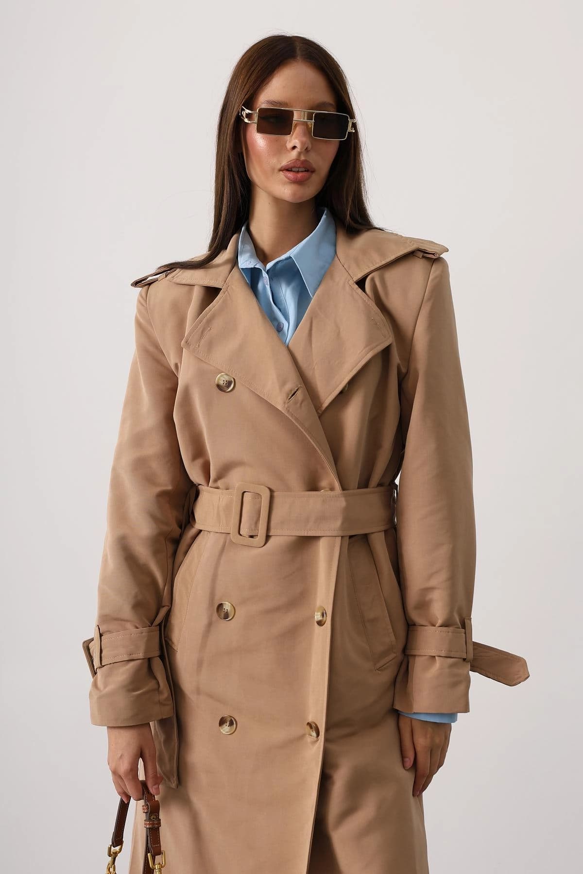 A buff ladies' rain-resistant garment, presenting shoulder flaps, a two-row front closure, and secured arm cuffs.